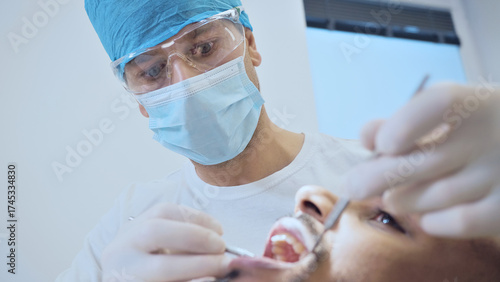 A focused dentist in surgical attire examines a patient's mouth, highlighting precision and care in dental health. The clinical setting underscores professionalism, emphasizing the importance.