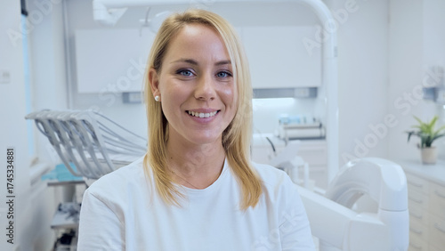 Free Download A smiling female dentist in a modern, clean dental office, wearing a white coat and surrounded by dental equipment. The headshot emphasizes professionalism, care, and dental health. - GFXLoad