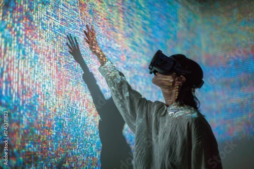 Person wearing a virtual reality headset reaches a hand toward a colorful abstract digital projection wall.