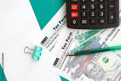Nigerian naira money bills and calculator with tax form on flag. Taxation and accounting concept