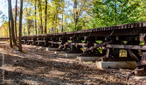 Obraz na plátně A wooden trestle bridge stands tall among vibrant autumn trees