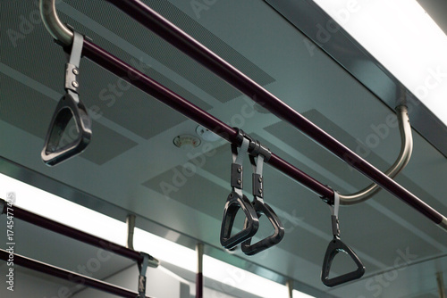 Train handrails and straps in modern transportation system. The image emphasizes metal and fabric design of the hand grips, showcasing practical and functional element of public transit