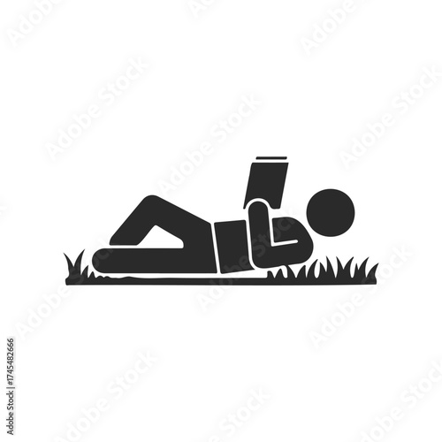 Silhouette of person relaxing and reading on grass