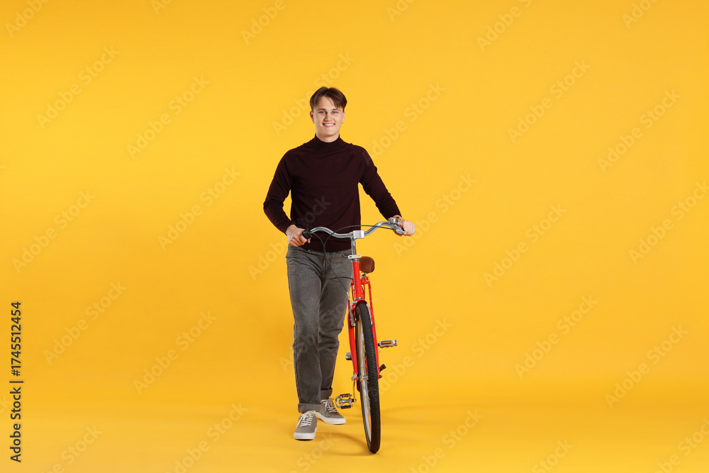 Fototapeta premium Handsome man with red bicycle on orange background