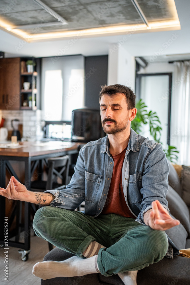 Fototapeta premium Man practicing mindful meditation in living room at home