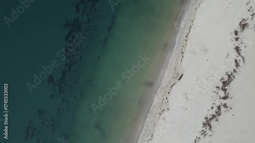 Aerial ascending drone footage of a pristine beach, showcasing turquoise waters, white sandy shores, and natural wave patterns in Rías Baixas, Galicia, Spain  
