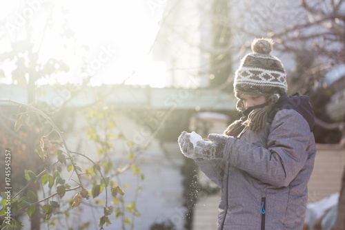 Boy holding snow in hands on sunny winter day outdoors