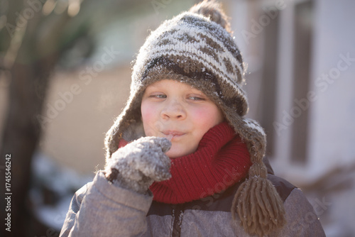 Boy licking icicle in sunlight winter curiosity and discovery horizontal