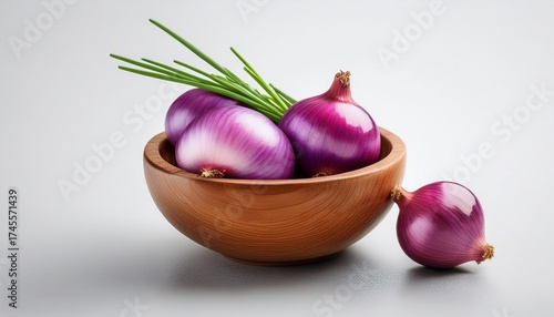 A Small Wooden Bowl Filled With Purple Shallots And Green Stems With One Shallot Resting Outside On A Clean White Background