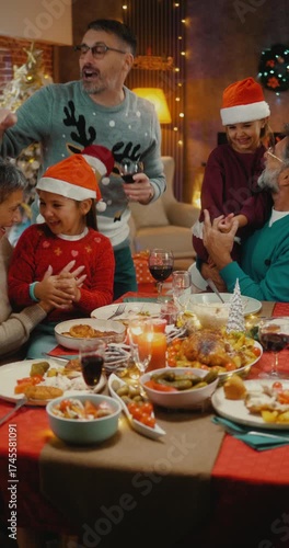 Vertical video of joyful multigenerational family singing Christmas songs at dinner table. Festive home atmosphere filled with music, laughter, and holiday spirit.