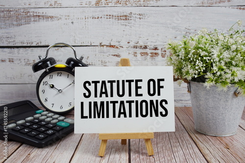 Foto Statute of Limitations text with alarm clock and calculator on wooden background