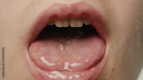 Extreme close-up macro video of a young person's healthy pink tongue, glistening with clear saliva and intricate papillae, subtly shifting against a soft grey bokeh, scientific observation