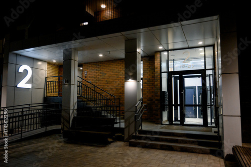 Street entrance to an apartment building with landscaping elements.