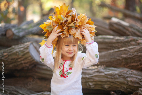 Joyful Girl Celebrating Autumn With a Colorful Crown of Leaves in a Beautiful Outdoor Setting During Halloween Season