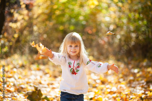 Joyful Girl Playing Among Colorful Autumn Leaves in a Beautiful Outdoor Setting During Halloween Season