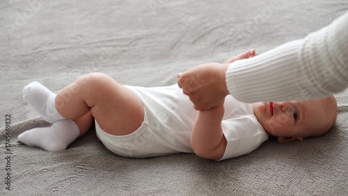 Baby lies on its back and sucks its thumb, mother removes infant's hand from its mouth, and baby begins to cry shrilly. Mom soothes crying infant with rattle. Caring for baby