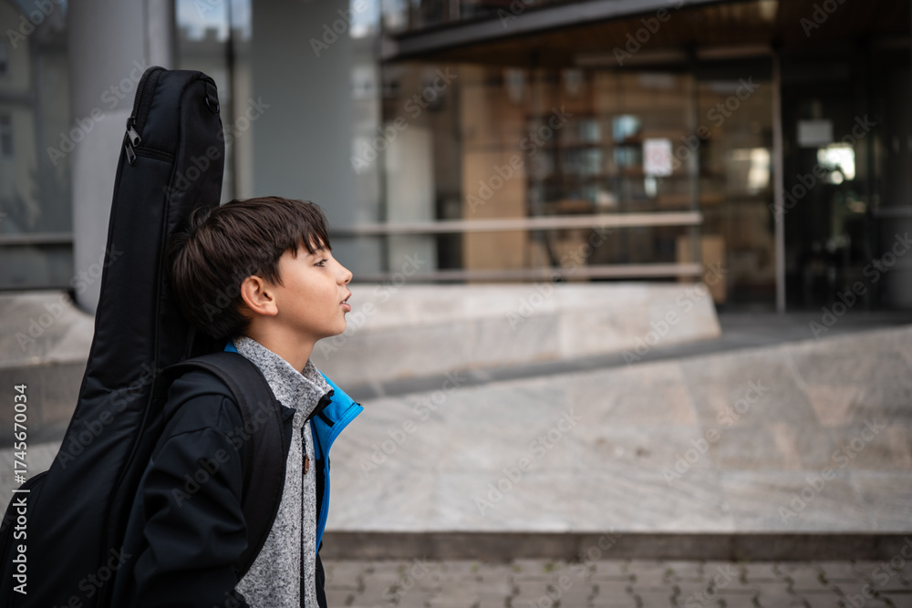 Fototapeta premium Boy carrying guitar case going to music school