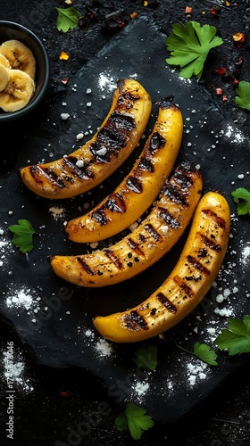 Top View Grilled Bananas with Salt on Stone Plate with parsley on black background