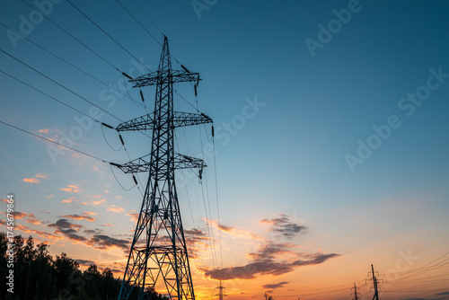 A tall power tower is silhouetted against a beautiful sunset sky