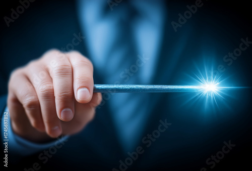businessman's hand pointing with a magic wand, emitting a glowing light blue beam against a dark background