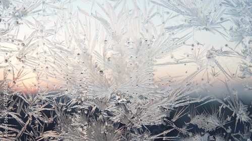Ice patterns on window against backdrop of city skyline at dawn, close up. Water and condensation crystallize on glass in subzero temperatures.