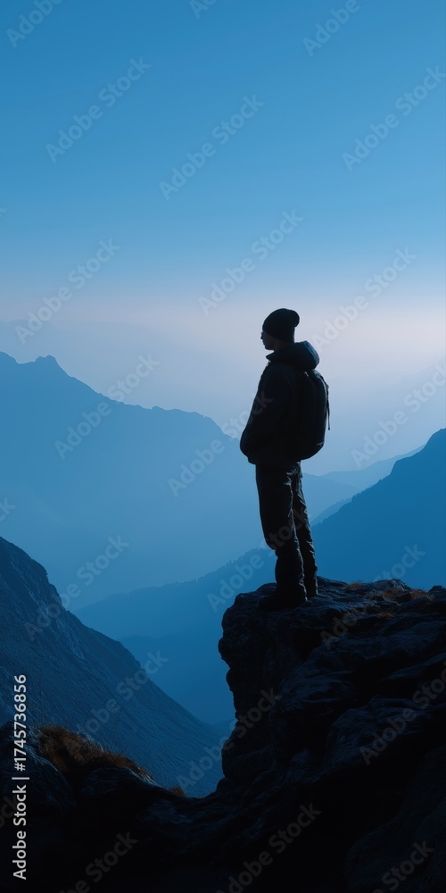Fototapeta premium Silhouette of male hiker overlooking majestic mountain landscape at dawn