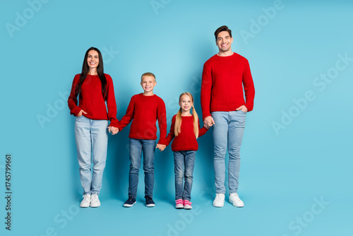 Obraz na plátne Family in matching sweaters posing against blue background embracing togethernes