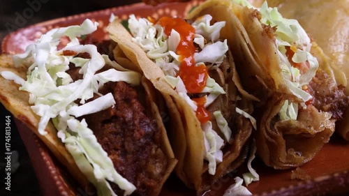 Extreme close up of red hot salsa being poured with a spoon on traditional mexican steamed tacos