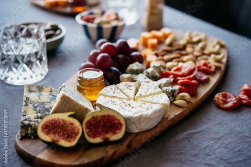 Wooden board with different kinds of cheese and dry fruit snacks. Dinner or celebration party concept.