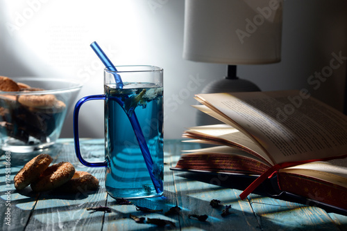 Blue butterfly pea tea in glass cup with cookies on blue wooden table