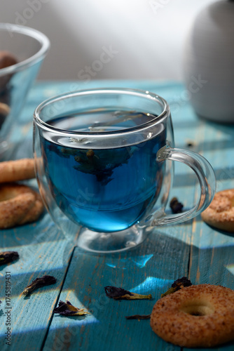 Blue butterfly pea tea in glass cup with cookies on blue wooden table