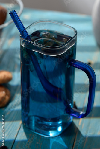 Blue butterfly pea tea in glass cup with cookies on blue wooden table