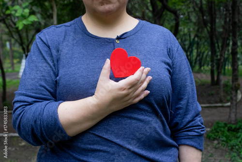 An obese woman holds a heart because she is worried about her health.