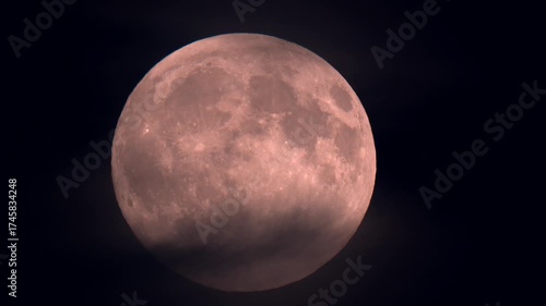 Harvest supermoon rising though clouds