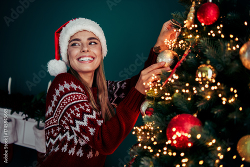Canvas Print Playful Santa helper decorates a beautiful Christmas tree smiling in a cozy home