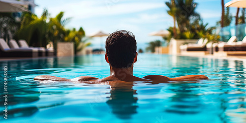 A smiling man in sunglasses enjoys relaxing in an azure pool at a luxury resort. The atmosphere evokes a summer vacation, tranquility, and high style.