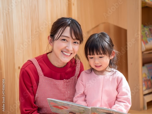 Plakat 保育士の女性が幼児と絵本を一緒に読む笑顔あふれる保育園での温かいふれあいの写真