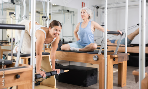 Young woman doing pilates exercises with a reformer bed