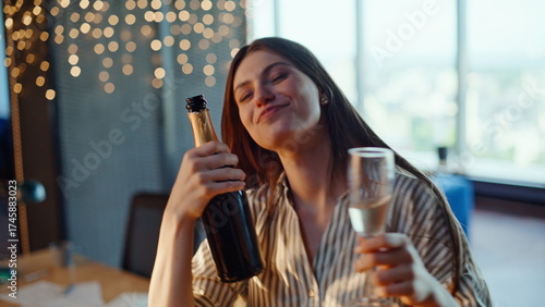 Drunk businesswoman moving body freely in workplace with alcohol bottle closeup