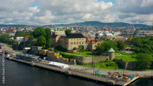 Aerial establishing footage of Akershus Castle and Fortress with Oslo waterfront and skyline. Historic architecture meets modern cityscape under clear summer skies in Norway capital. 4K zoom in shot