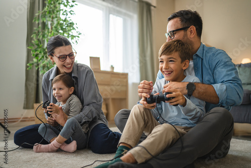Tablou pe pânză Happy family of 4 enjoys quality time together, play a video game