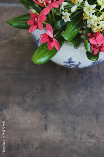 Vaso de cerâmica branco com flores do campo brancas e rosadas sobre fundo marrom rústico.
White ceramic vase with white and pink wildflowers on a rustic brown background