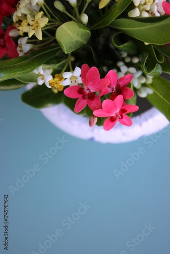 Vaso de cerâmica branco com flores do campo brancas e rosadas sobre fundo azul claro. Espaço vazio, mockup, foto vertical, White ceramic vase with white and pink wildflowers on a light blue background