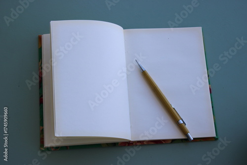 Caderno aberto sobre base neutra, com lapiseira amarela sobre a folha branca.
Open notebook on a neutral background, with a yellow mechanical pencil on the white page.