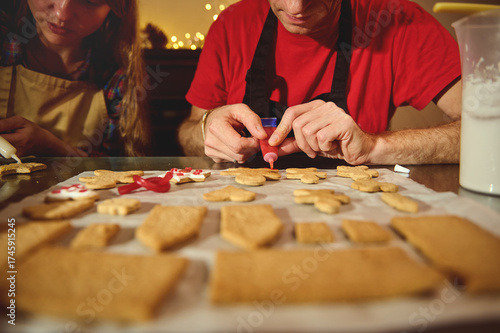Friends And Family Bake Christmas Cookies At Home, Decorating With Icing On A Cozy Kitchen Counter