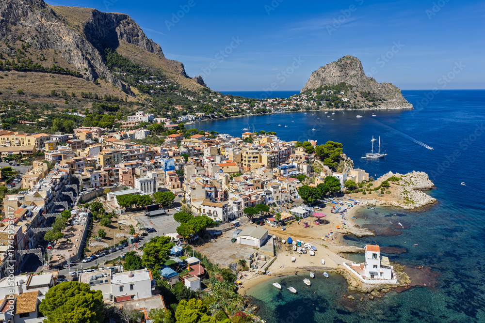 Obraz premium Sant Elia bay beach in Porticello town, Santa Flavia, Sicily, Italy, aerial drone view of Sicilian turquoise waters, rocky cliffs, colorful houses, and Mediterranean coastline panorama in Bagheria