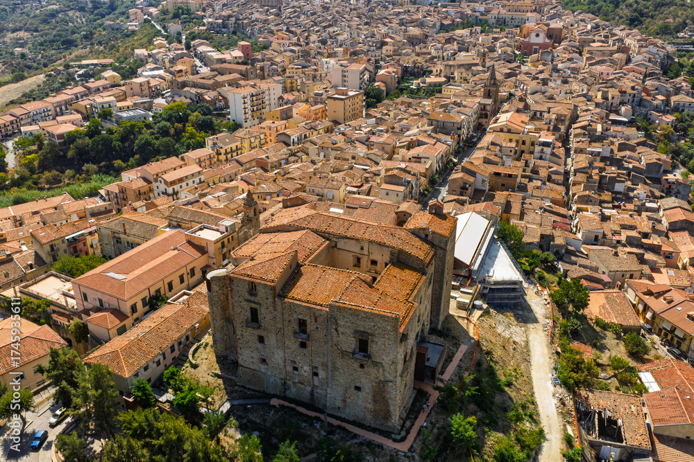 Naklejka premium Aerial drone view of Castelbuono medieval town in the Madonie Mountains, Sicily, Italy, basking under the summer sun with historic streets, Ventimiglia Castle. Old mountain town in Sicily