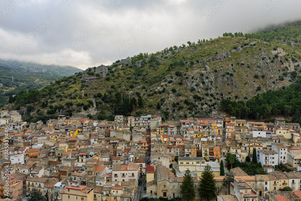 Naklejka premium Aerial drone view of Collesano Sicilian mountain town at sunset with Basilica San Pietro church and historic stone streets in the Madonie Mountains, Sicily, Italy. Old mountain town in Sicily