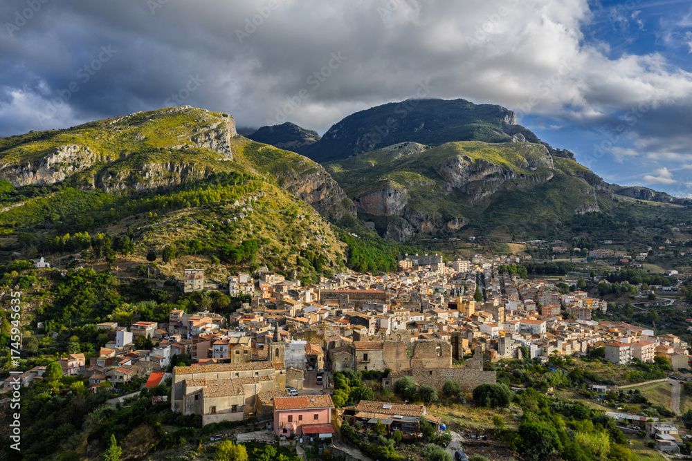 Naklejka premium Aerial drone view of Collesano Sicilian mountain town at sunset with Basilica San Pietro church and historic stone streets in the Madonie Mountains, Sicily, Italy. Old mountain town in Sicily