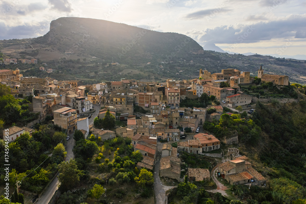 Fototapeta premium Aerial drone view of Collesano Sicilian mountain town at sunset with Basilica San Pietro church and historic stone streets in the Madonie Mountains, Sicily, Italy. Old mountain town in Sicily